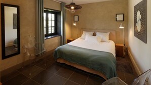 Un dormitorio con cama, ventana, espejo y lámpara colgante.
