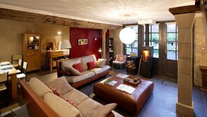 Una sala de estar acogedora con chimenea, un sofá, una mesa de centro y un comedor con sillas y una mesa.