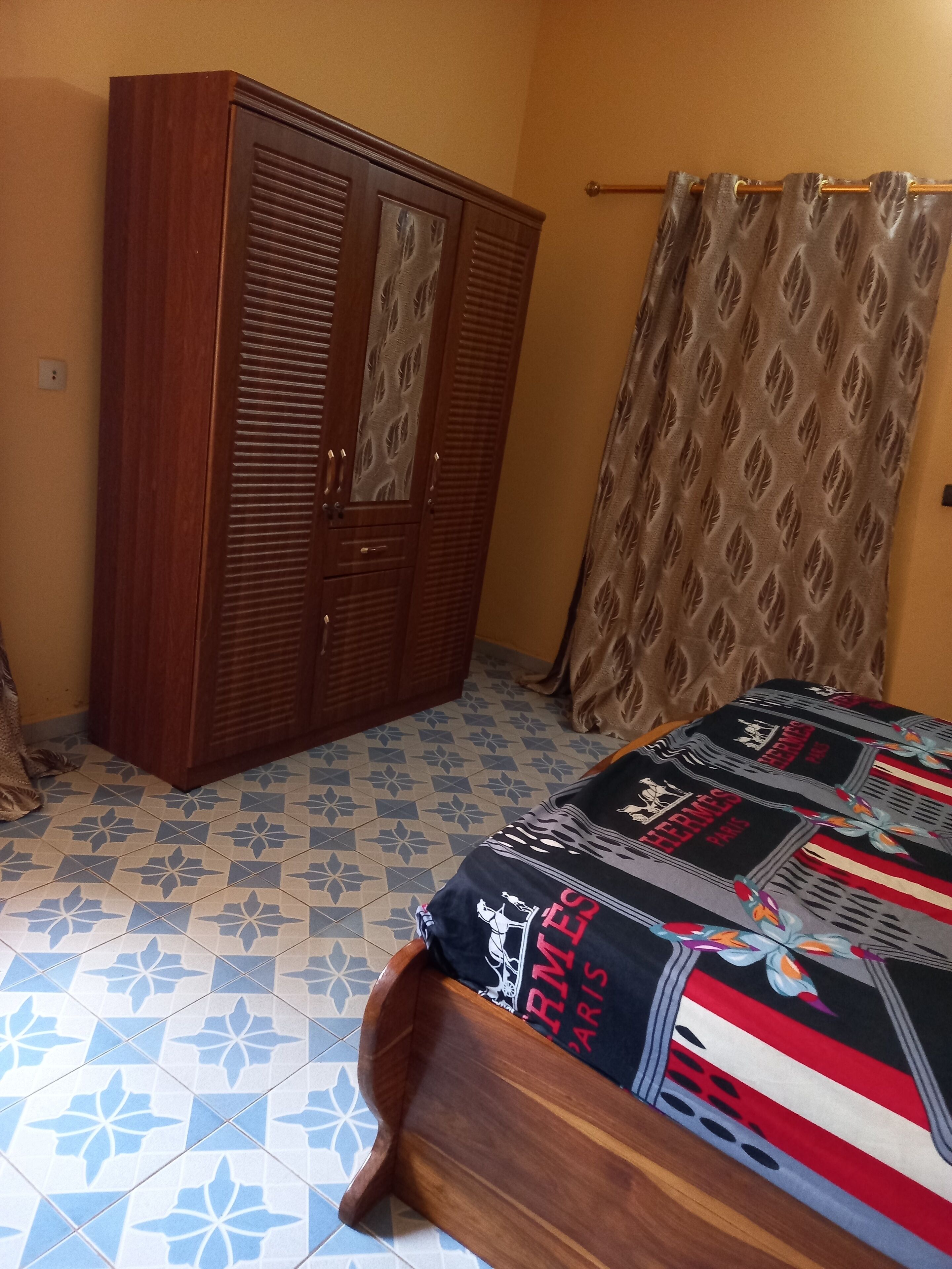 Ein Schlafzimmer mit einem Bett, einem Kleiderschrank und Vorhängen mit Muster.