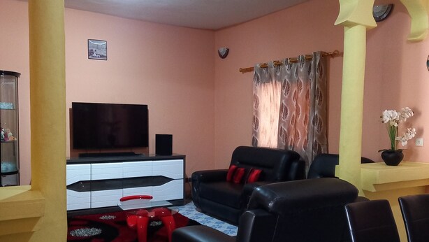 A living room with a black sofa, a TV, and a patterned floor.