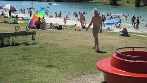 Eine Strandansicht mit badenden und sonnenden Personen.