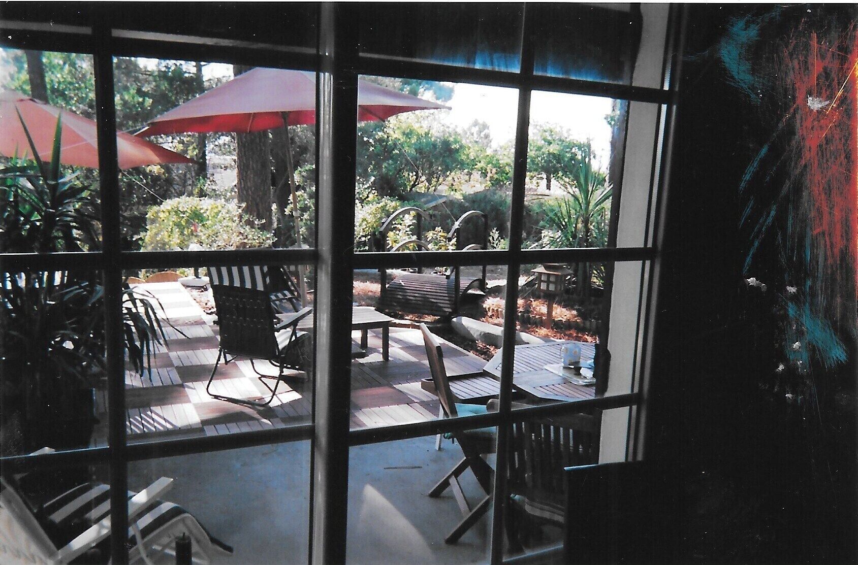 Un patio con mobiliario exterior, incluyendo sillas y una mesa, y dos sombrillas rojas.