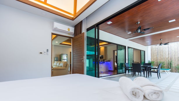 Una habitación de hotel moderna con una cama grande, un baño con puerta de vidrio y un área de comedor con una mesa y sillas.
