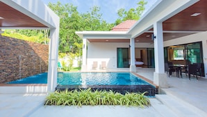 Una casa moderna con piscina, zona de estar exterior y pared de ladrillo.