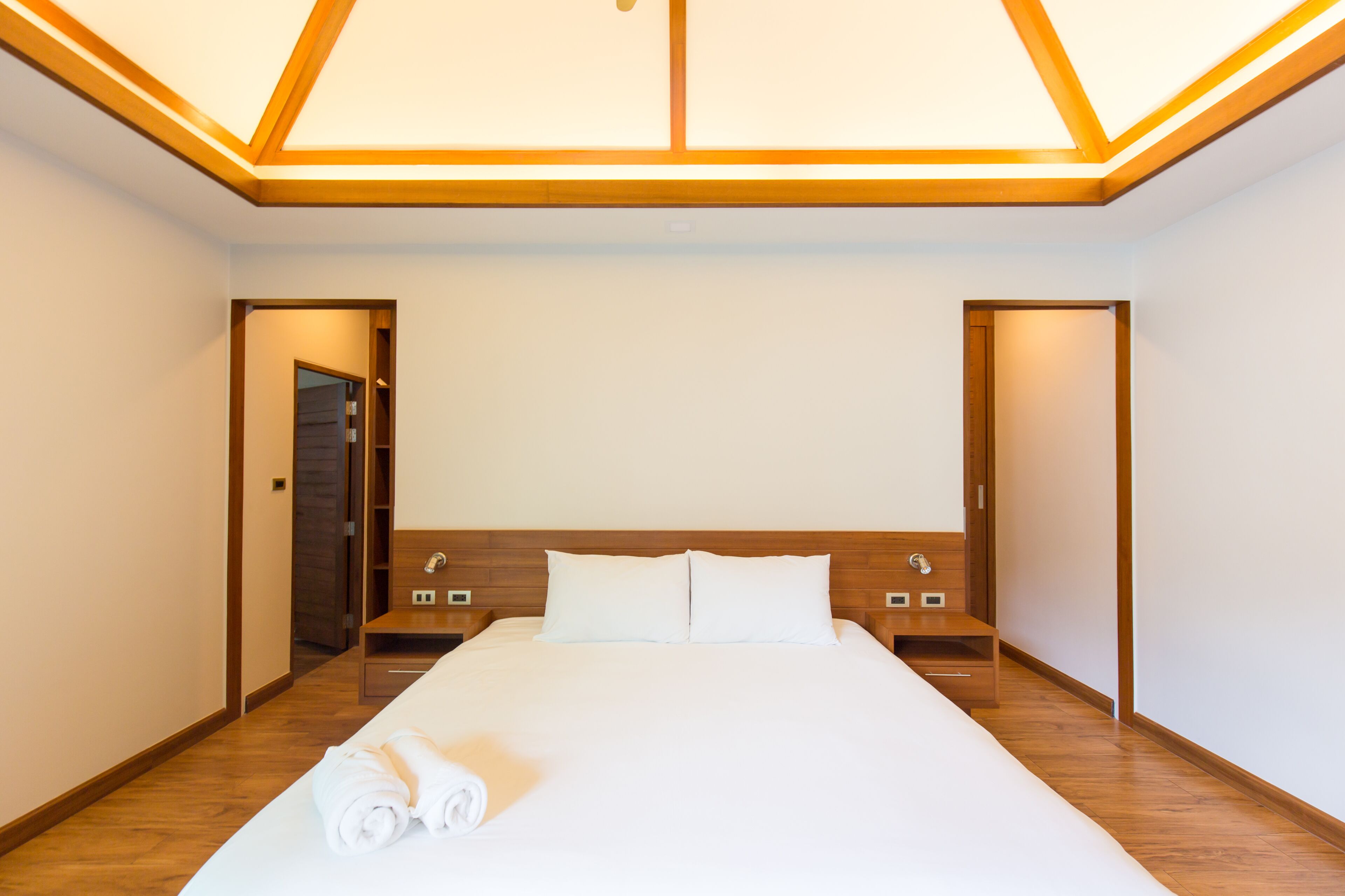 A hotel room with a large bed, wooden headboard, and a skylight.
