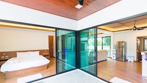 Habitación de hotel moderna con una cama grande, un separador de vidrio, una kitchenette y un ventilador de techo.
