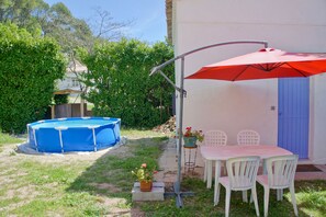 Relax by the serene pool surrounded by lush greenery and a shaded dining area.