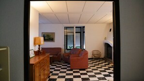 Um quarto com piso xadrez, lareira, sofá e abajur.