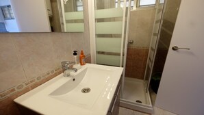 A bathroom with a white sink, a mirror, and a glass shower enclosure. - SEA VIEW STUDIO (Benalmádena)