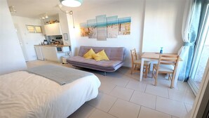 A modern hotel room with a large bed, a sofa, a dining table with chairs, a kitchenette, and a view of the beach. - SEA VIEW STUDIO (Benalmádena)