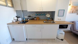 A compact kitchen with a sink, stove, and a small refrigerator. - SEA VIEW STUDIO (Benalmádena)