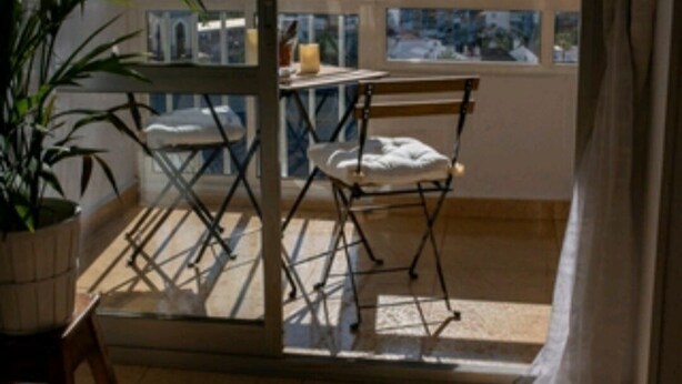 A balcony with a table and chairs, a potted plant, and a view of a cityscape. - SEA VIEW STUDIO (Benalmádena)