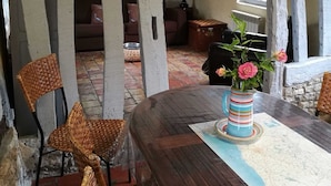 Un coin repas avec une table en bois, des chaises en osier et un vase rempli de fleurs.