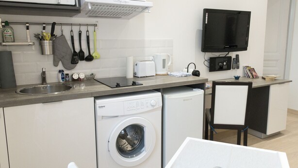 A compact kitchen with a washing machine, a coffee maker, and a microwave. - Studio 24-Studio-Apartment-Wet room-Garden view (Vittel)