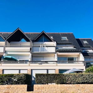 A multi-story building with a modern architectural design, featuring balconies and large windows.