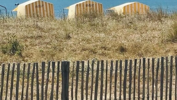 Vista sulla spiaggia con tre cabine da bagno a righe, etichettate 'BIG' e 'BIG1'.