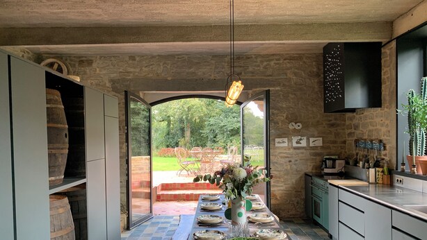 Una cocina moderna con una isla grande, paredes de piedra y vistas a un jardín.
