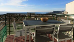 Varanda com mesa e cadeiras, com vista para a costa.