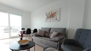 Uma sala de estar moderna com um sofá cinza, uma poltrona cinza e uma pequena mesa redonda com uma tigela.