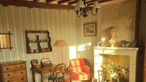 A traditional room with a bed, wooden furniture, a fireplace, and a mirror on the wall. - Pretty stone house, 3 bedrooms, 2 bathrooms with a large enclosed garden (Longues-sur-Mer)