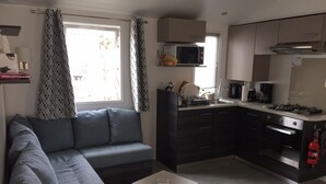 Un espace de vie compact comprenant un canapé, une petite table, une kitchenette équipée d’un four à micro-ondes, d’une cuisinière et de placards.