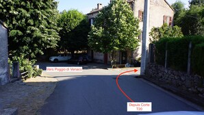 A narrow street with parked cars and a stone wall on one side.