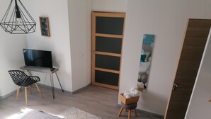 A bedroom with a bed, a desk with a chair, a wardrobe, and a door.
