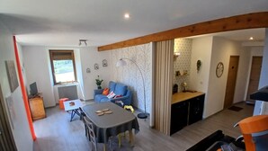 A modern living space with a dining area, a sofa, a small table, and a kitchen area.