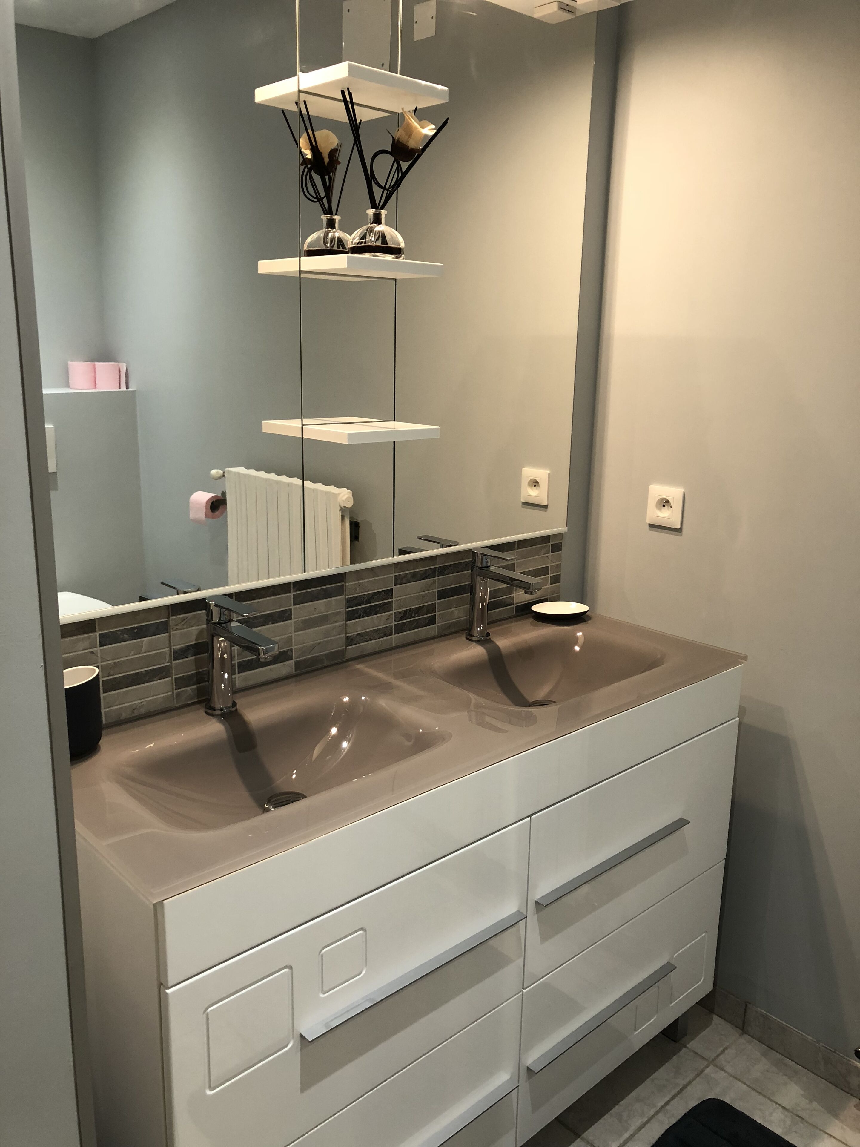 A modern bathroom with two sinks, a large mirror, and a white vanity with drawers.