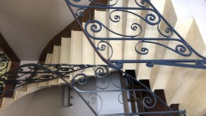 Eine Treppe mit aufwendiger, schwarzer Metallgeländerung und beigen Wänden.