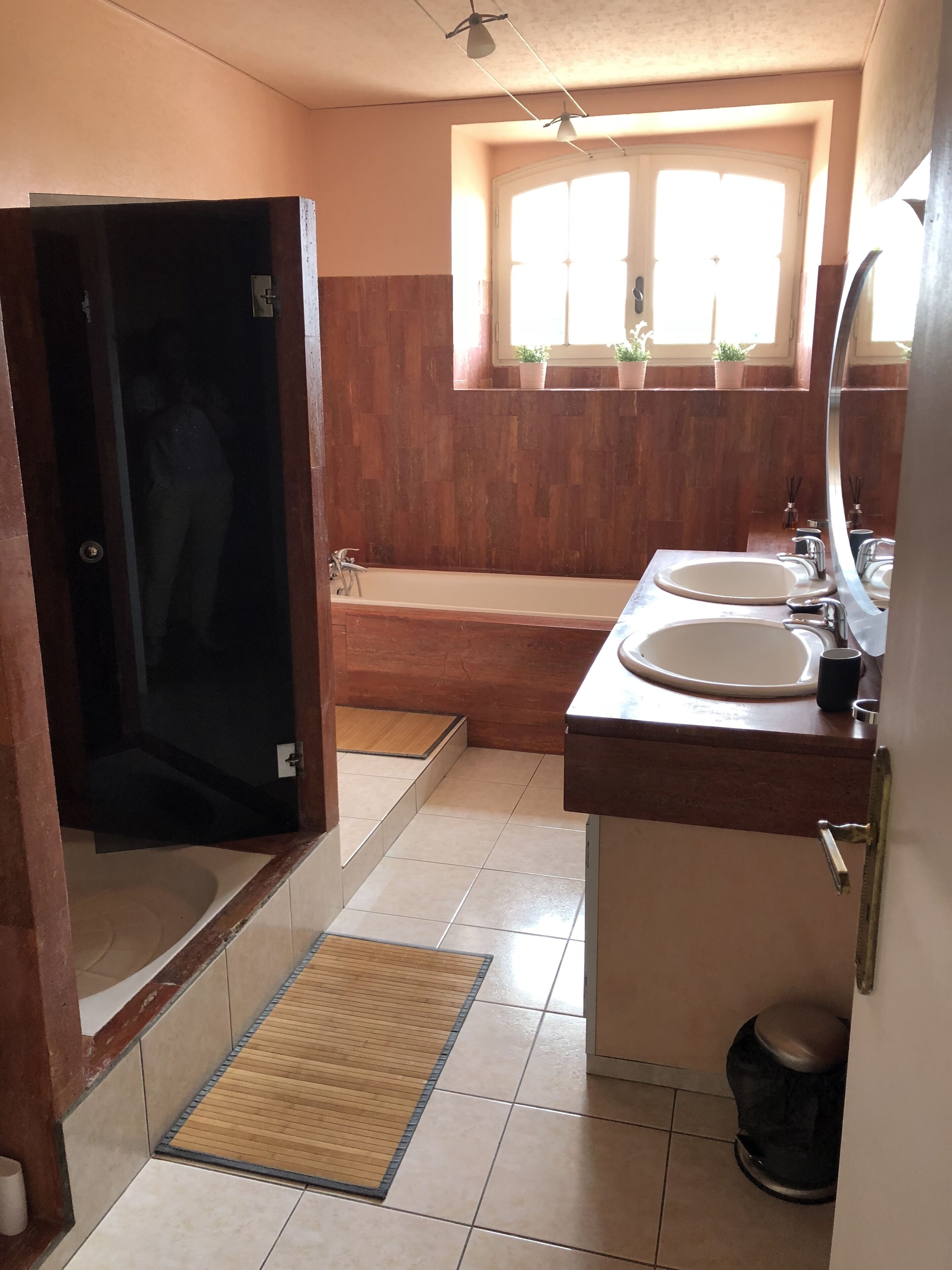 Une salle de bain avec une baignoire, deux lavabos, une fenêtre et un porte-serviettes.