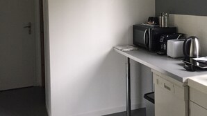 Un meuble blanc avec une machine à café posée dessus.