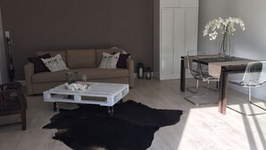 Un salon moderne comprenant un canapé, une table basse et un coin repas avec une table et des chaises.