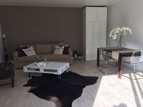 Uma sala de estar moderna com um sofá, mesa de centro e um espaço de jantar com mesa e cadeiras.