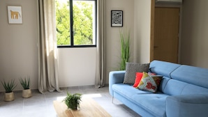 Un salon moderne avec un canapé bleu, une table basse en bois et des plantes en pot.