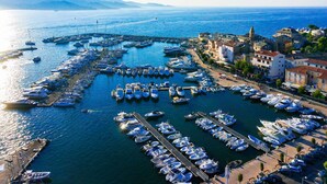 Un port de plaisance où de nombreux bateaux sont amarrés, entouré de bâtiments et offrant une vue dégagée sur la mer.