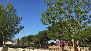 A playground with a white picket fence, trees, and a clear blue sky. - Holiday home - Gruissan les Ayguades - 6 people (Gruissan)