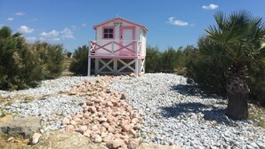 A small, single-story building with a pink and white exterior, situated on a rocky terrain with sparse vegetation. - Holiday home - Gruissan les Ayguades - 6 people (Gruissan)