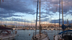A marina with multiple sailboats docked, a clear sky, and buildings in the background. - Holiday home - Gruissan les Ayguades - 6 people (Gruissan)