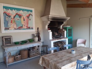 A rustic dining area with a wooden table, chairs, a fireplace, and a painting on the wall. - Loft with pool in Provence (CARPENTRAS)