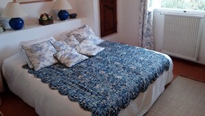 A bedroom with a bed, two lamps, a window with curtains, and a radiator.