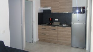 A compact kitchen with wooden cabinets, a built-in microwave, a stainless steel refrigerator, and a black countertop. - LAST MINUTE T2 N ° 2 HC (Cavalaire-sur-Mer)