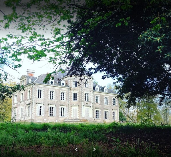Stately historic building with a classical facade, surrounded by lush greenery.