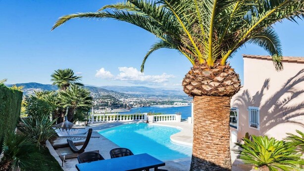 A poolside area with a palm tree, lounge chairs, and a view of the sea and cityscape. - ★ House with Panoramic Sea View ★ (Théoule-sur-Mer)