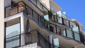 A multi-story building with balconies, each with black metal railings.