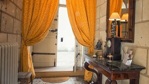 Ein Zimmer mit gemusterten Bodenfliesen, einem Holztisch mit Lampe und einem großen Spiegel.
