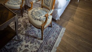 Ein Schlafzimmer mit einem Bett, zwei Stühlen, einem kleinen Tisch und einem Nachttisch.