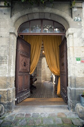 Un arco de entrada con un letrero con el número 79, una puerta de madera y una cortina.