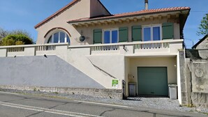 Een tweelaags huis met garage, schuin dak en een klein balkon.