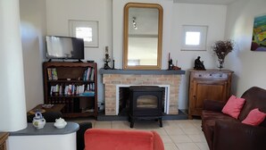 Een woonkamer met een open haard, een televisie, een boekenkast en een bank.